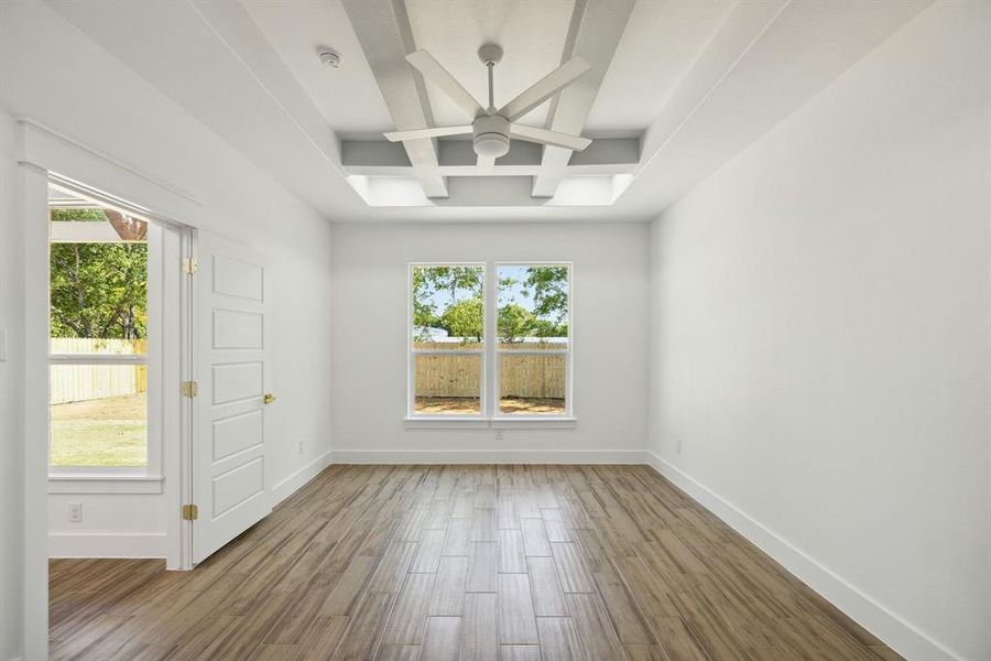 Unfurnished room featuring beam ceiling, hardwood / wood-style flooring, coffered ceiling, and ceiling fan