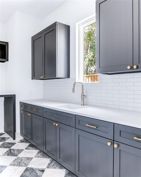 Kitchen with sink, decorative backsplash, and gray cabinetry