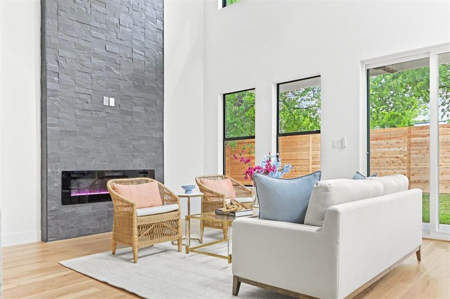 Living room featuring a wealth of natural light, a towering ceiling, and light hardwood / wood-style floors