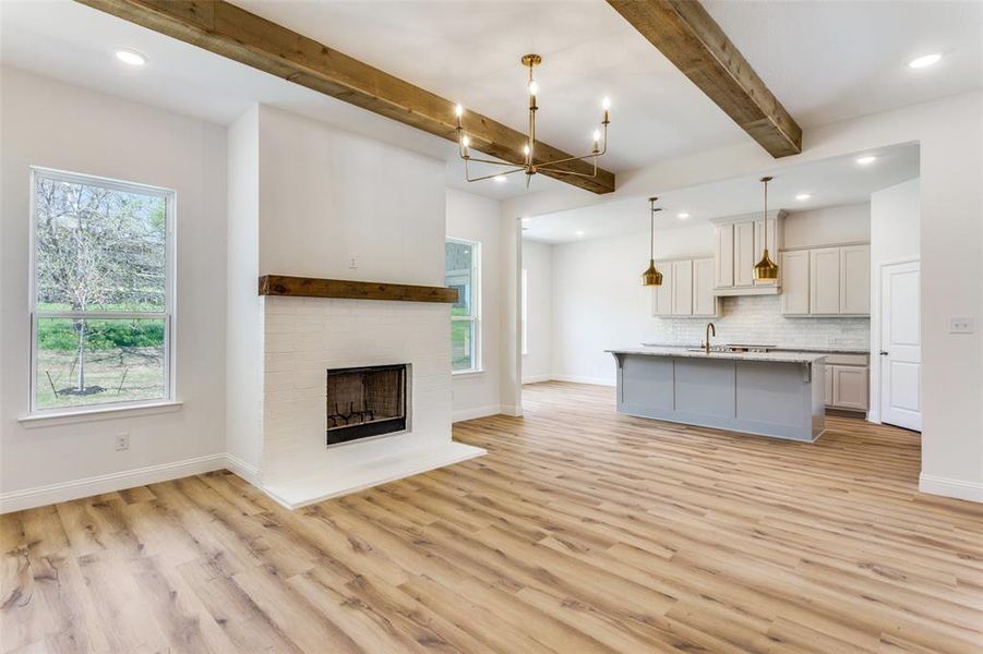 Unfurnished living room with plenty of natural light, sink, light hardwood / wood-style floors, and a fireplace