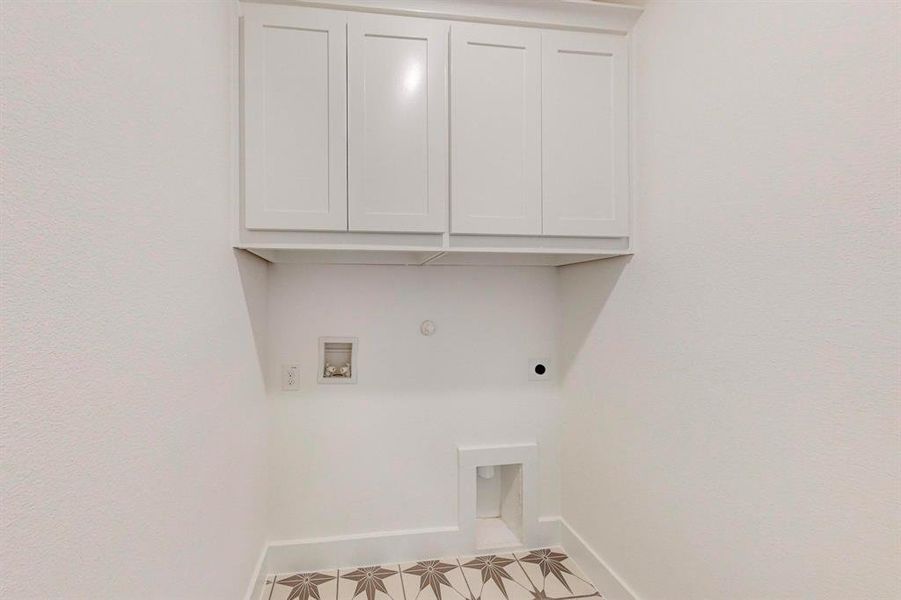 Clothes washing area featuring hookup for a washing machine, tile patterned flooring, cabinets, hookup for an electric dryer, and gas dryer hookup