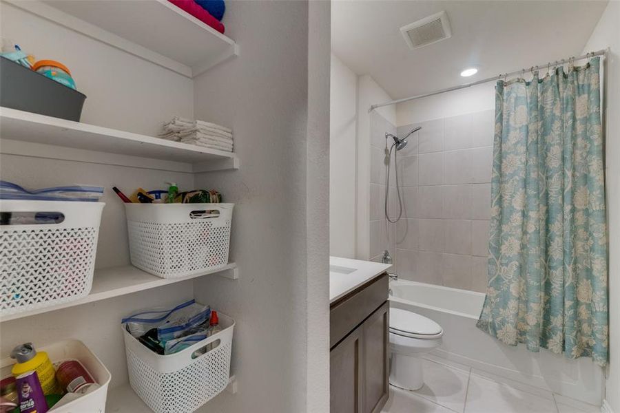 Full bathroom with tile patterned floors, shower / bathtub combination with curtain, toilet, and vanity