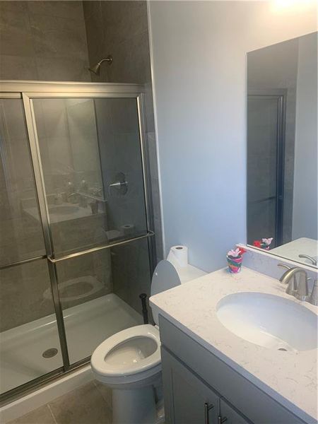 Bathroom featuring toilet, a shower with door, oversized vanity, and tile flooring