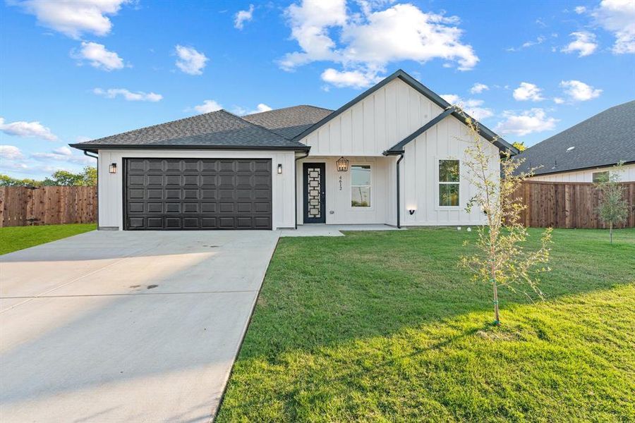 Modern farmhouse featuring a front yard and a garage