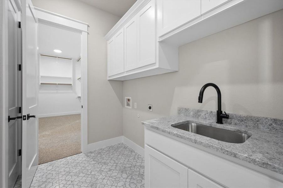 Washroom featuring hookup for a washing machine, hookup for an electric dryer, sink, light colored carpet, and cabinets