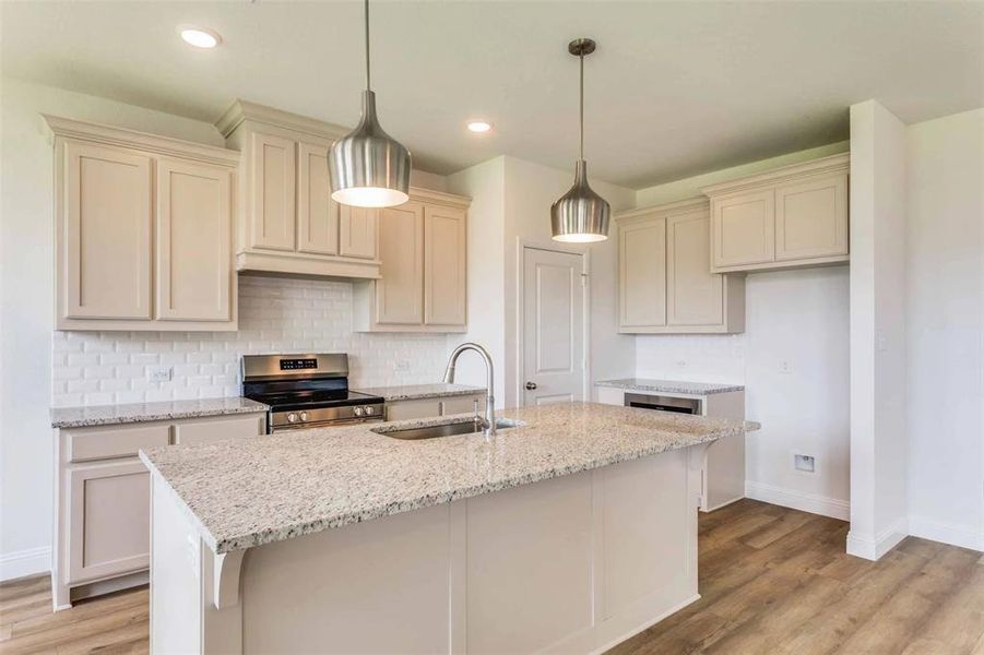 Kitchen featuring stainless steel range with gas cooktop, light hardwood / wood-style floors, sink, and an island with sink