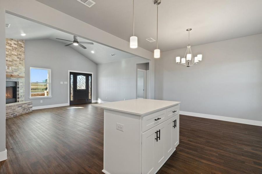 Kitchen featuring a center island, dark hardwood / wood-style floors, white cabinetry, hanging light fixtures, and a stone fireplace