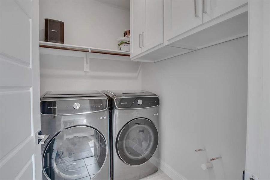 Clothes washing area featuring separate washer and dryer and cabinets