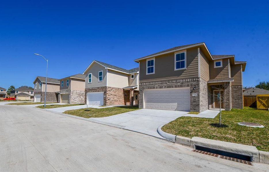 New suburban houses with two-story structures, garages, and clear blue skies.