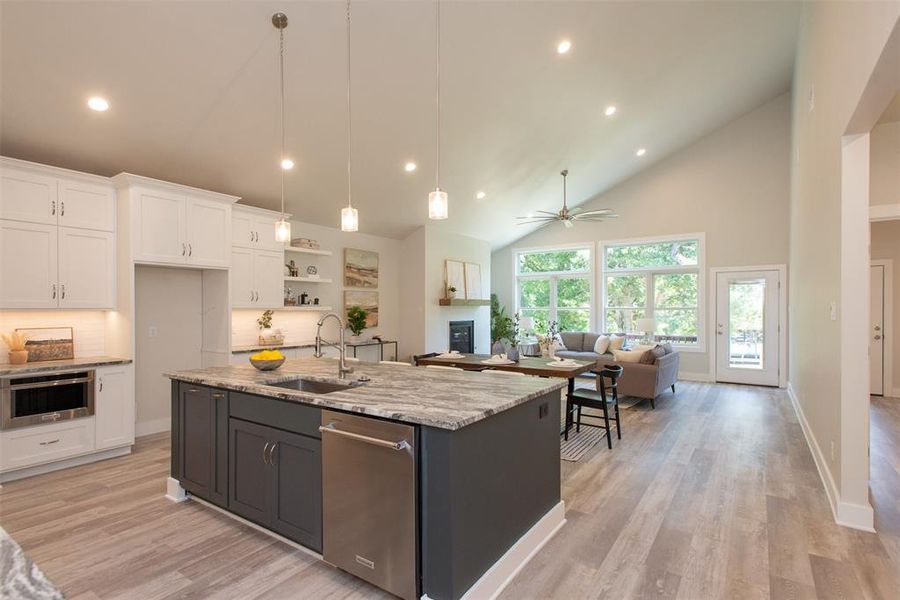 Kitchen with pendant lighting, sink, custom cabinets, center island high vaulted ceiling, and ceiling fan