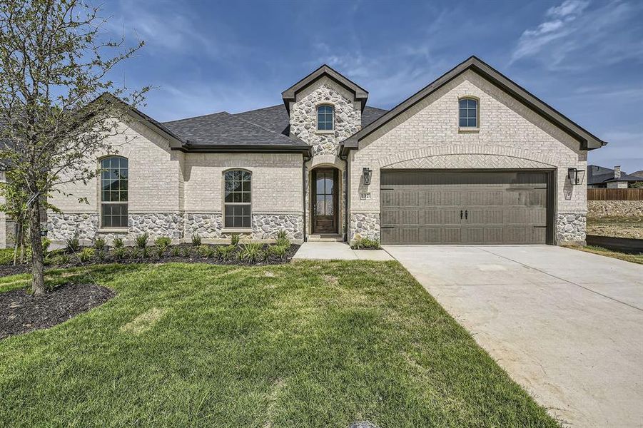 French country home with a garage and a front lawn