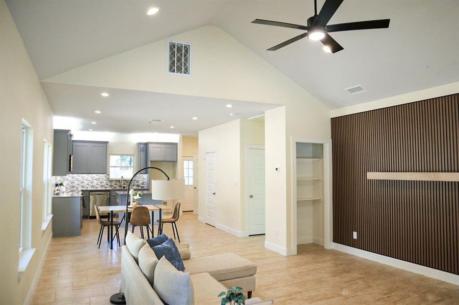 Living room featuring light hardwood / wood-style floors, high vaulted ceiling, and ceiling fan