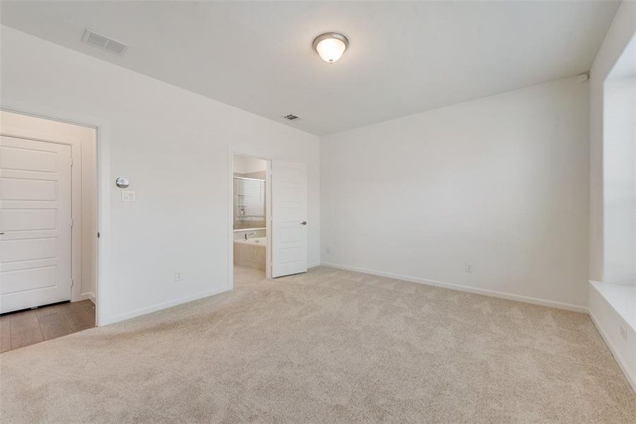 Unfurnished bedroom featuring ensuite bath, light carpet, and a closet