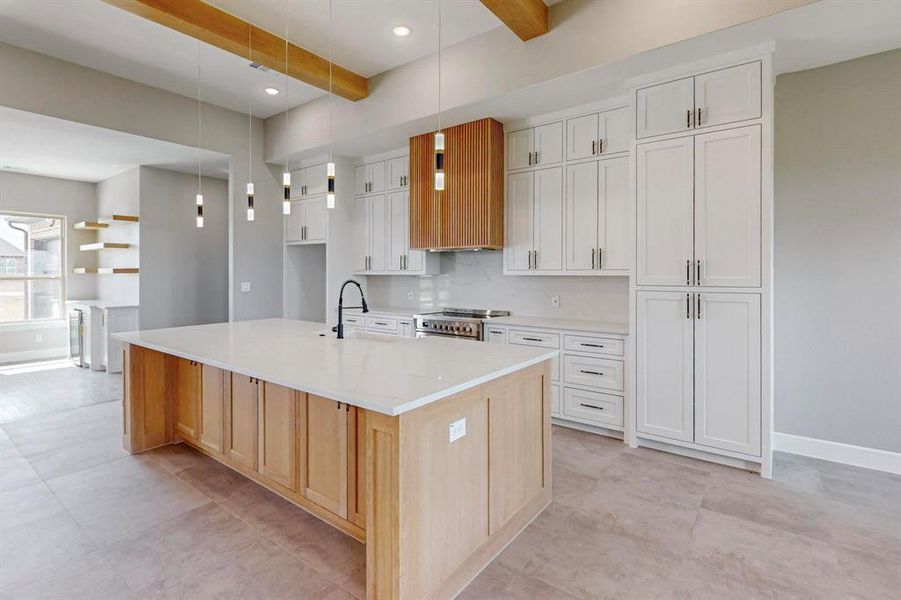 Kitchen featuring white cabinets, beam ceiling, stainless steel range, and a spacious island