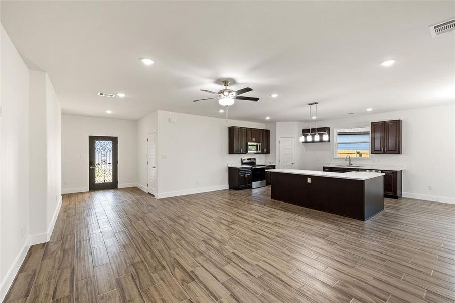 Kitchen featuring wood-type flooring, appliances with stainless steel finishes, a center island, and a healthy amount of sunlight