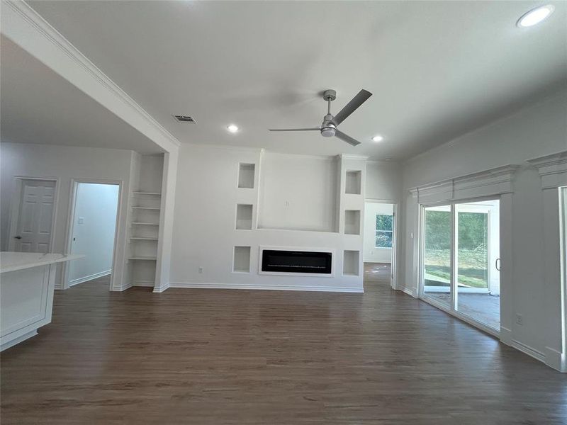 Living room featuring crown molding, dark wood-type flooring, and ceiling fan