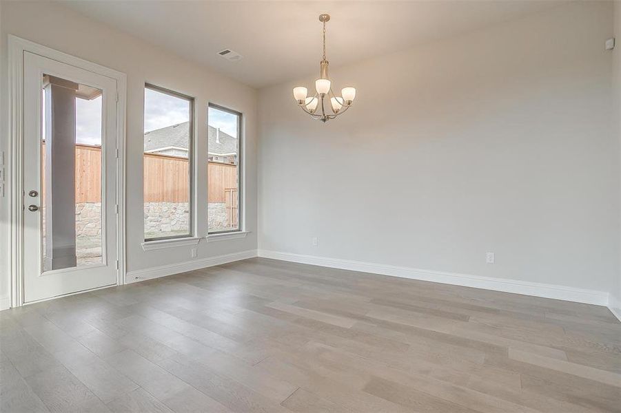 Spare room with a notable chandelier and hardwood / wood-style floors