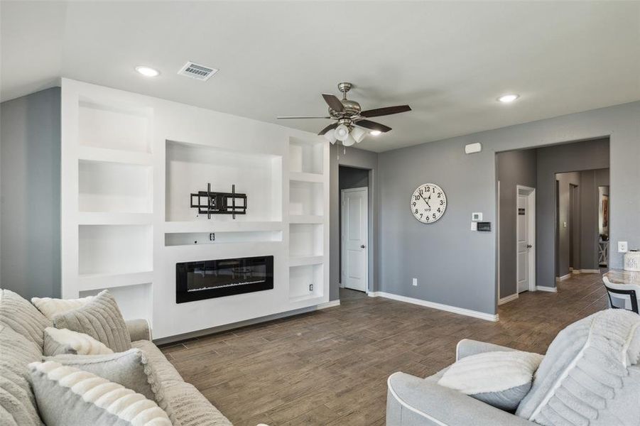 Living room featuring built in features, ceiling fan, and dark hardwood / wood-style flooring