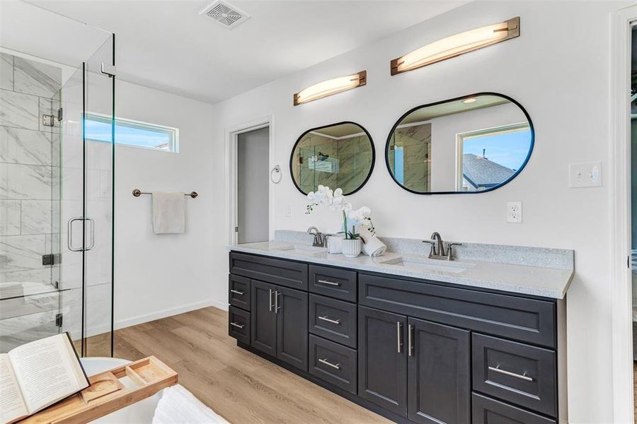 Bathroom featuring hardwood / wood-style flooring, dual vanity, and an enclosed shower