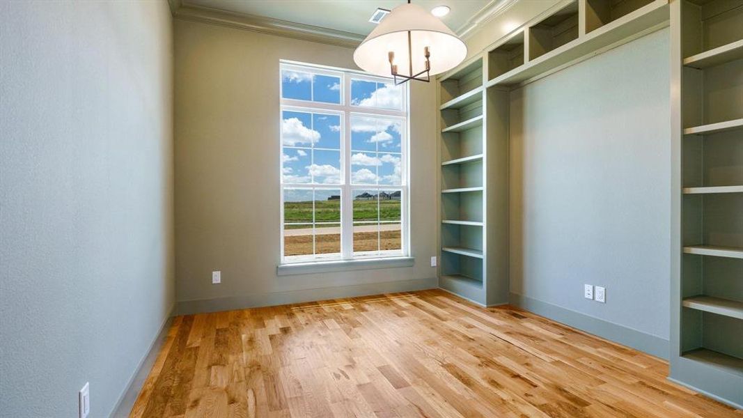 Spare room featuring light hardwood / wood-style floors, a notable chandelier, and ornamental molding