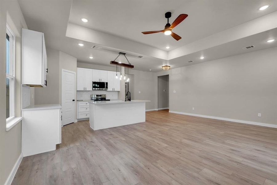 Kitchen featuring white cabinetry, stainless steel appliances, ceiling fan, and light hardwood / wood-style floors