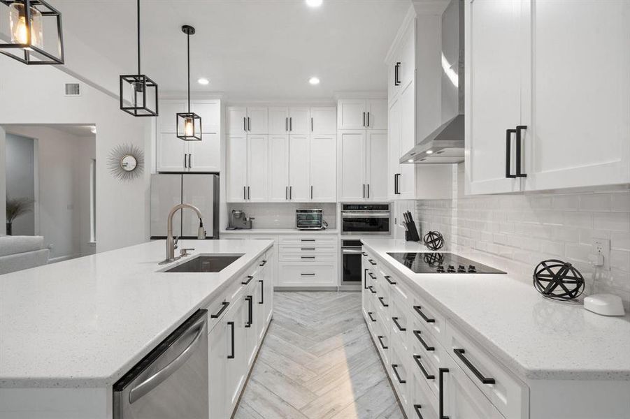 Kitchen featuring appliances with stainless steel finishes, hanging light fixtures, and white cabinetry