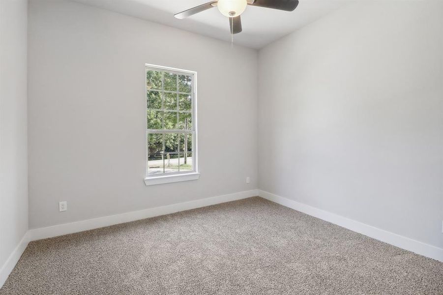 Carpeted spare room featuring ceiling fan