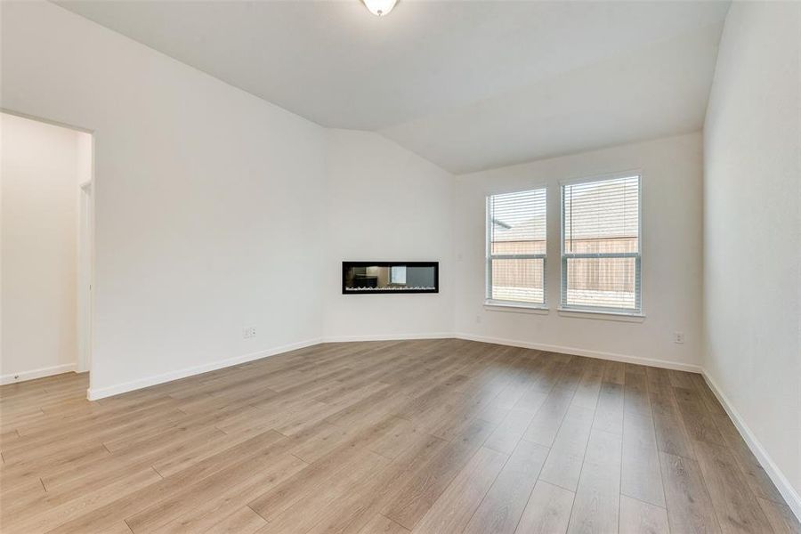 Unfurnished living room featuring lofted ceiling and light wood-type flooring