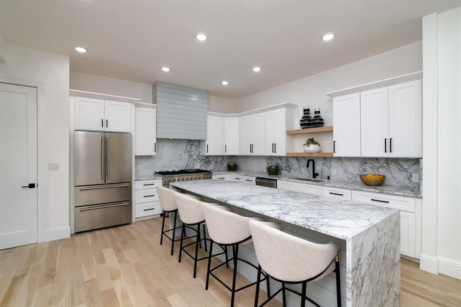 Kitchen featuring white cabinetry, light wood-type flooring, stainless steel appliances, and a center island