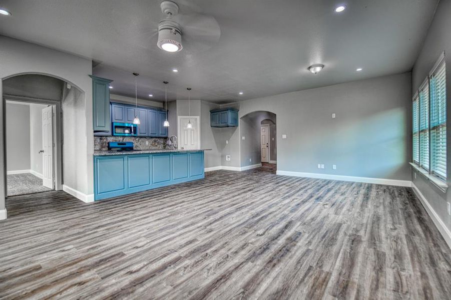 Kitchen with ceiling fan, tasteful backsplash, blue cabinetry, wood-type flooring, and hanging light fixtures