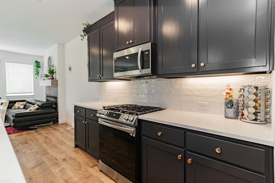 Kitchen with tasteful backsplash, light hardwood / wood-style flooring, and appliances with stainless steel finishes