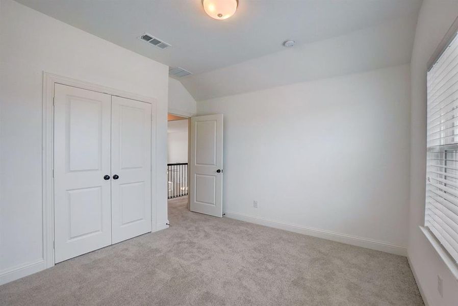 Unfurnished bedroom featuring a closet, vaulted ceiling, and light colored carpet