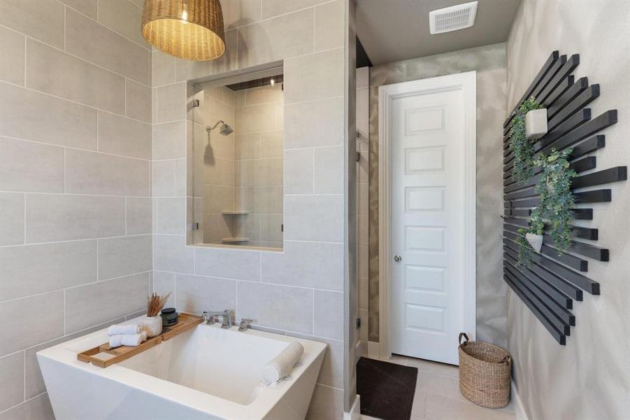 Bathroom featuring tile patterned floors, shower with separate bathtub, and tile walls