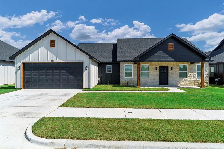 View of front of home with a garage and a front lawn