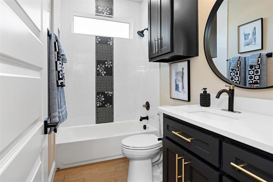 Full bathroom featuring tiled shower / bath combo, vanity, hardwood / wood-style flooring, and toilet