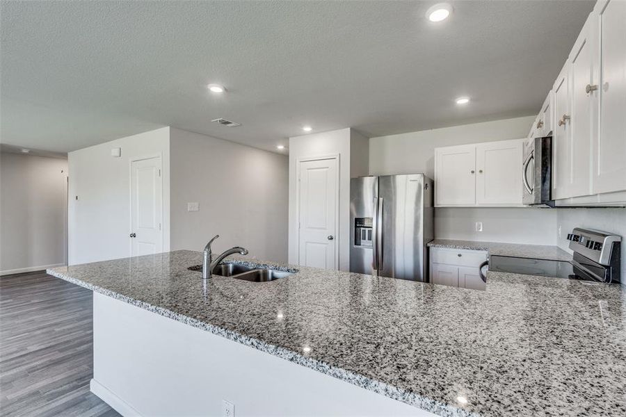 Kitchen featuring hardwood / wood-style flooring, sink, white cabinetry, kitchen peninsula, and appliances with stainless steel finishes