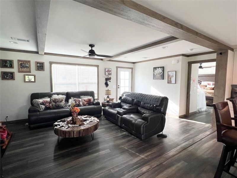 Living room with beam ceiling, dark wood-type flooring, and ceiling fan