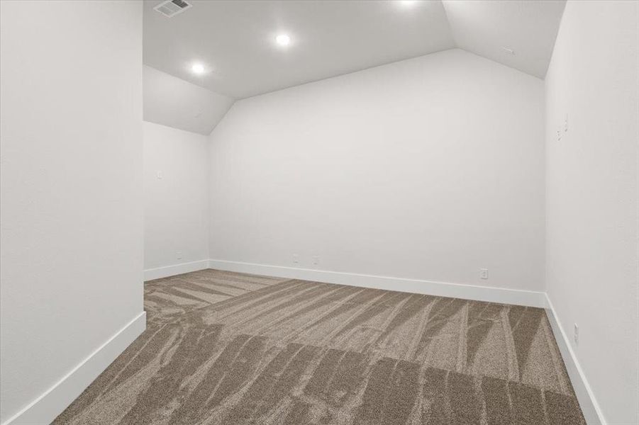 Empty room with lofted ceiling and carpet floors