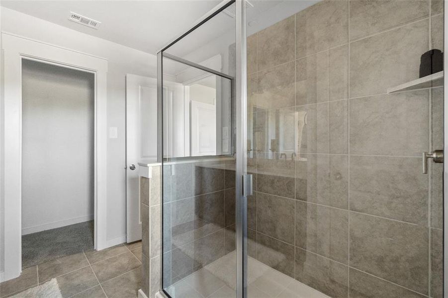 Bathroom with a shower with door and tile patterned floors