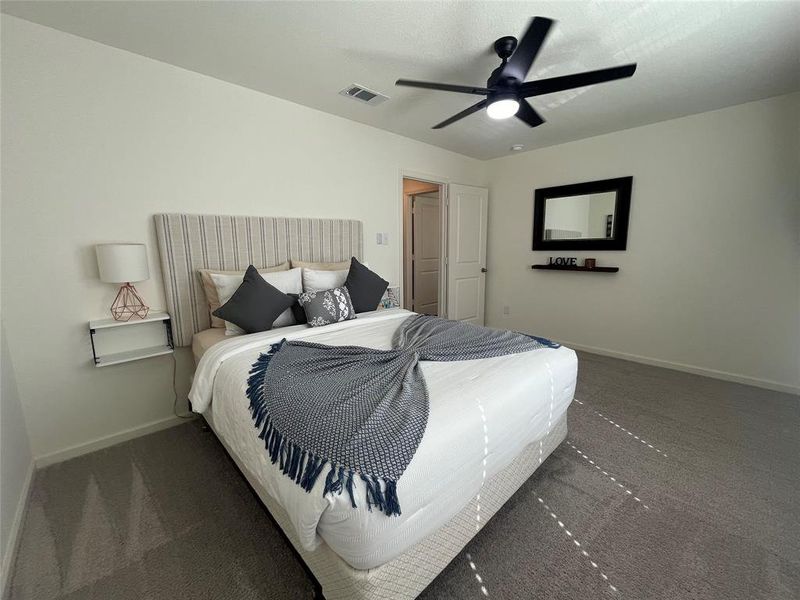 Bedroom with ceiling fan and dark colored carpet