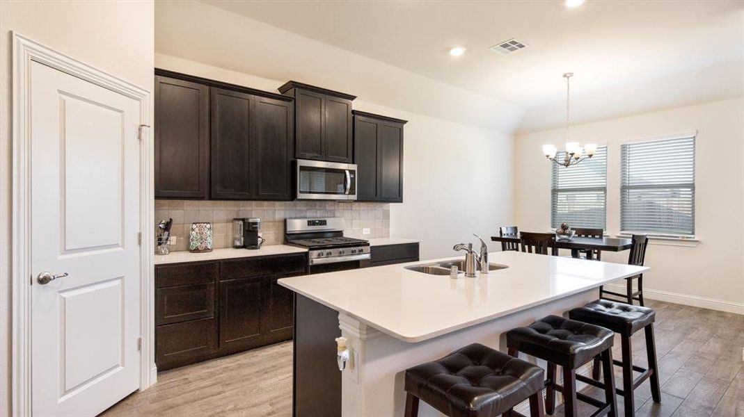 Kitchen featuring decorative backsplash, sink, stainless steel appliances, and light hardwood / wood-style floors