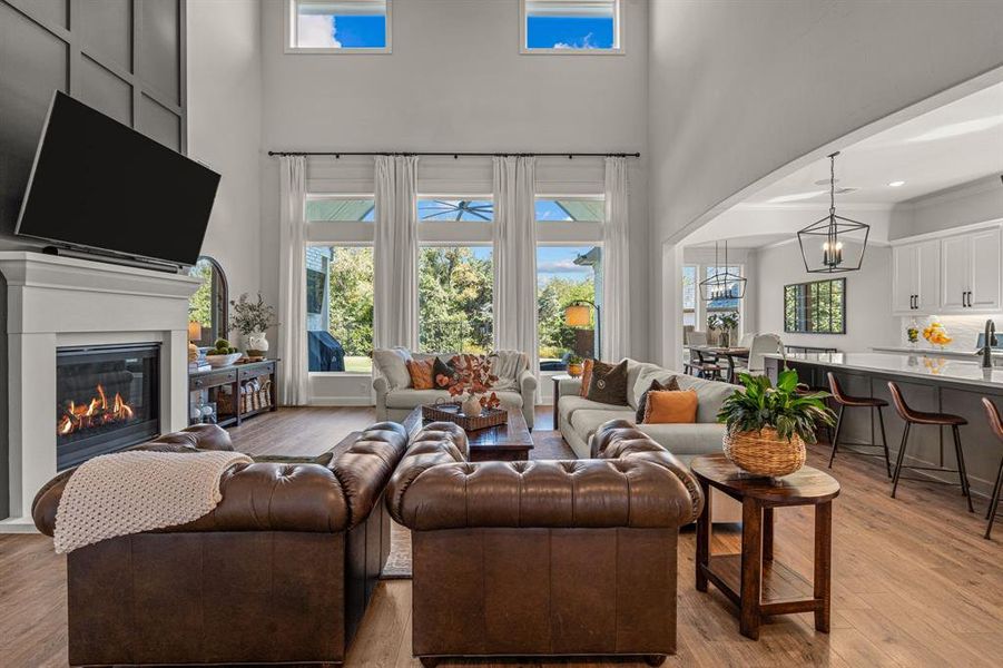 Living room with a towering ceiling, a chandelier, and light wood-type flooring