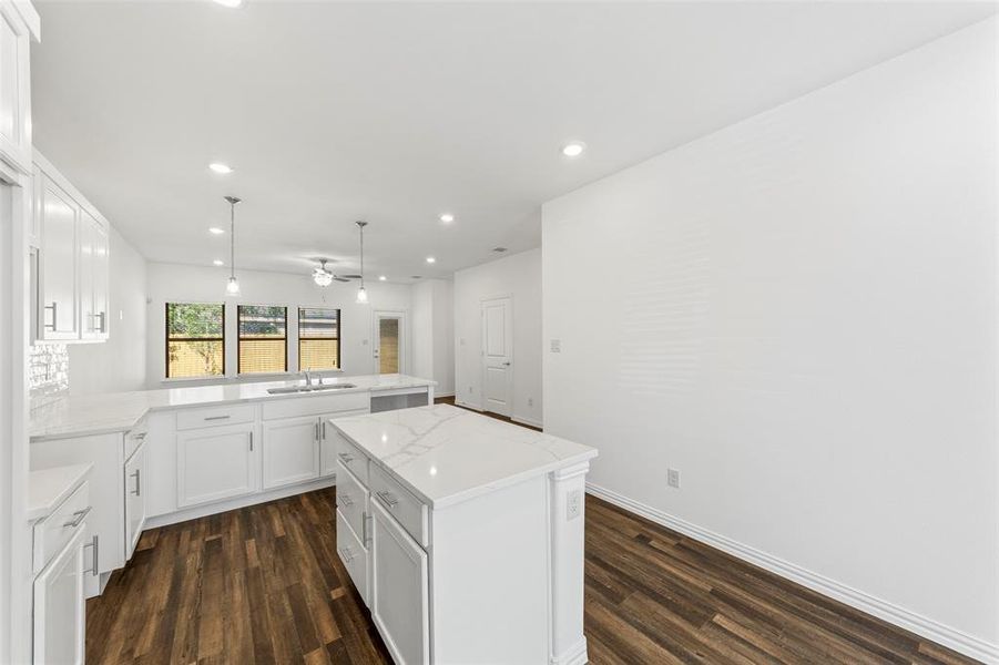 Kitchen featuring ceiling fan, sink, a kitchen island, dark wood-type flooring, and white cabinetry