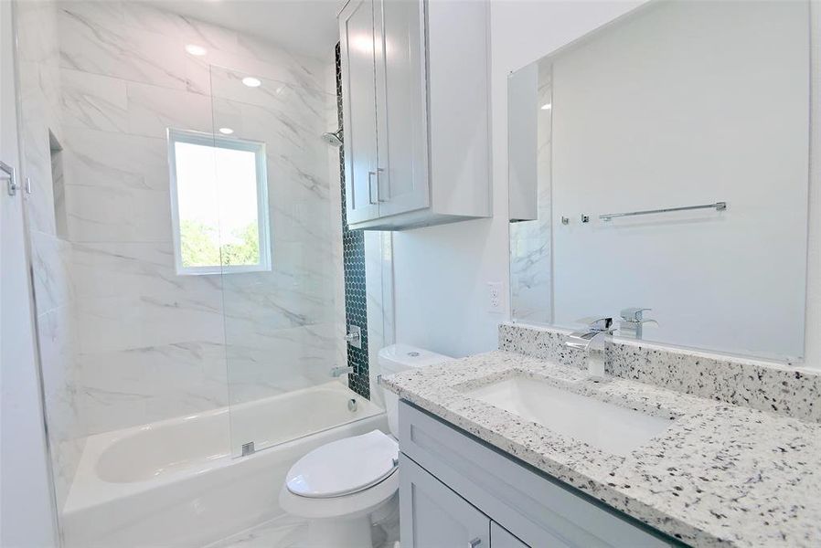 Full bathroom with tiled shower / bath, vanity, and toilet