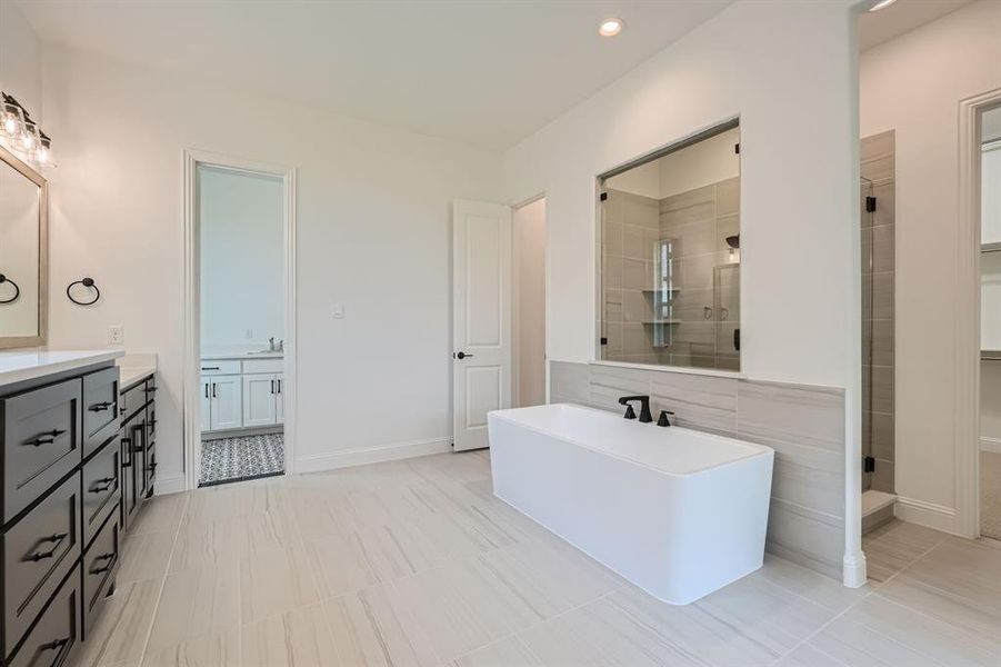 Bathroom featuring tile patterned flooring, separate shower and tub, and vanity