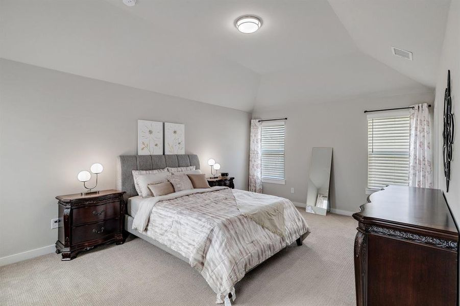 Bedroom with lofted ceiling and light colored carpet