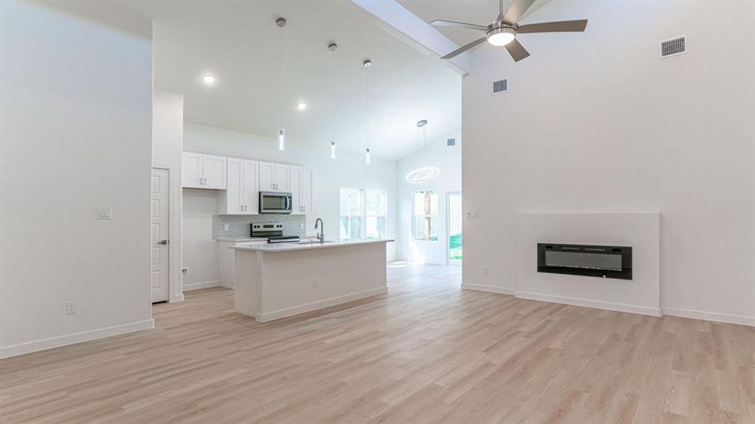 Living room with electric fireplace, high vaulted ceilings and ceiling fan