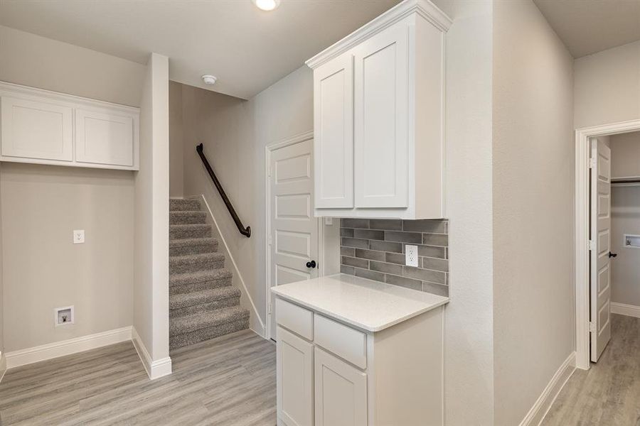 Kitchen with tasteful backsplash, light wood-type flooring, and white cabinets