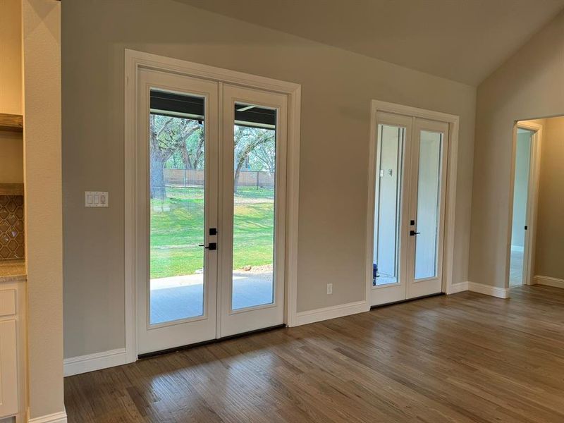 Entryway featuring french doors, vaulted ceiling, dark wood-type flooring, and a healthy amount of sunlight