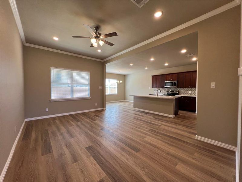 Unfurnished living room with ceiling fan with notable chandelier, ornamental molding, dark hardwood / wood-style flooring, and sink